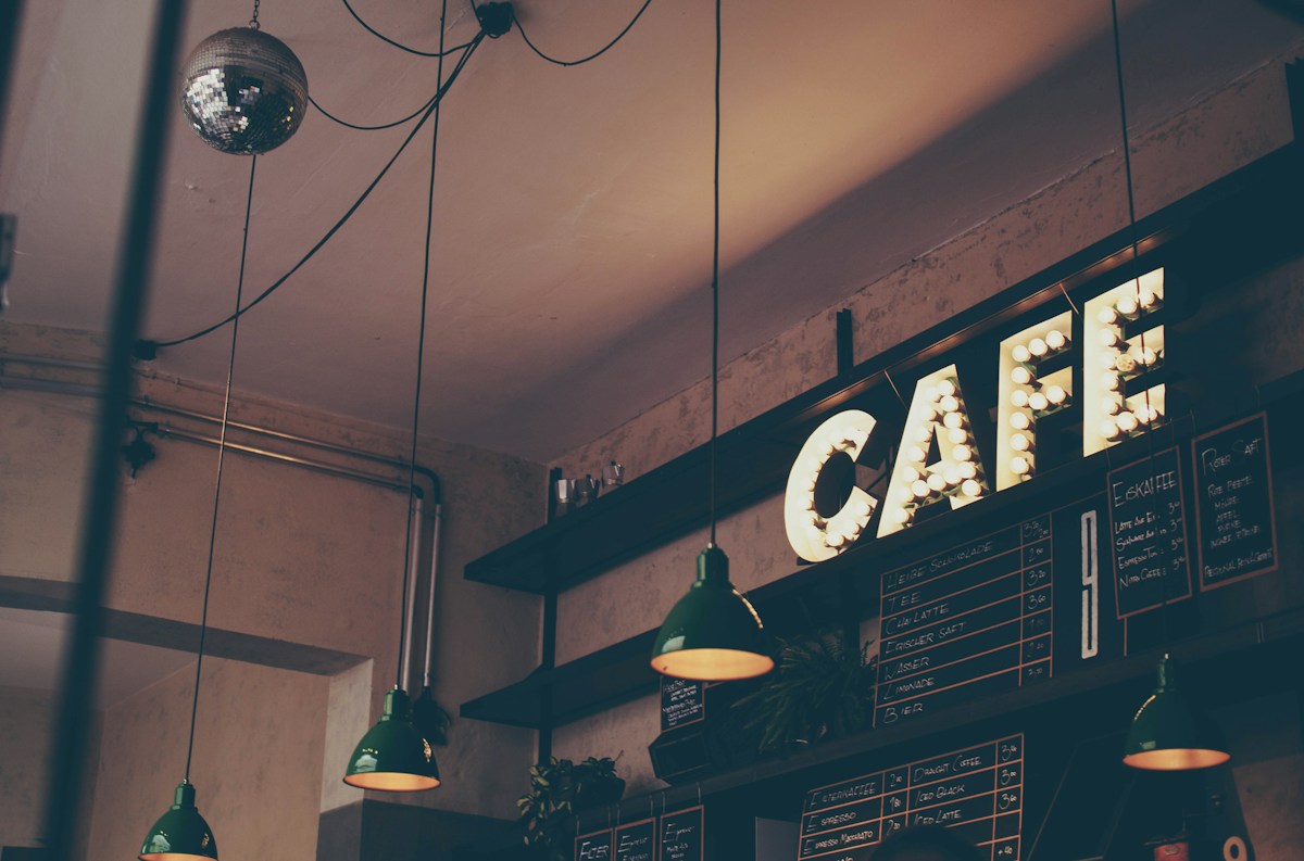 Warm café interior with pendant lights and a café sign